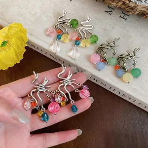Dettaglio di orecchini a nappa con perle di vetro colorate e accenti argento.