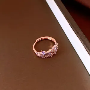 Detailed view of an elegant rose gold flower ring with purple and white zircons.