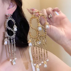 Dettaglio di orecchini a S in oro e argento con nappine di perle sulla modella