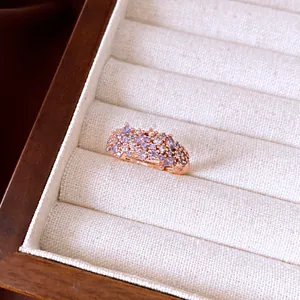 Detail view of a rose gold ring with purple and clear cubic zirconia in a jewelry box