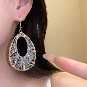 Elegant teardrop earrings featuring white woven thread and brilliant rhinestones.