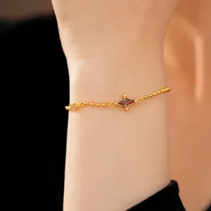 Elegant gold-plated bracelet featuring a purple rhombic zircon stone on a model's wrist