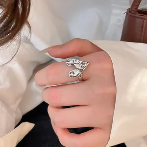 Close-up detail of a silver-colored wrinkled heart-shaped ring worn elegantly on a finger.