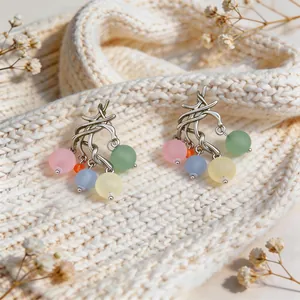 Dettaglio di orecchini in argento stile coreano con perle di vetro colorate opache