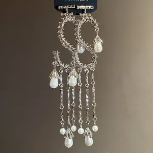 Vista dettagliata di orecchini a forma di S con eleganti nappe di perle a goccia.
