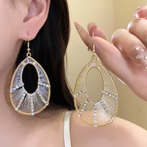 Close-up detail of teardrop hollow earrings with woven thread and sparkling rhinestones