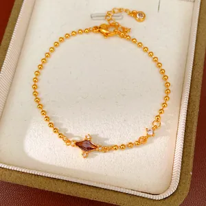 Detail view of a gold bead bracelet with a purple rhombus zirconia stone in a jewelry box.
