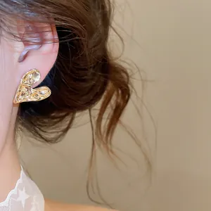 Detailed close-up view of elegant textured gold heart stud earrings worn by a model