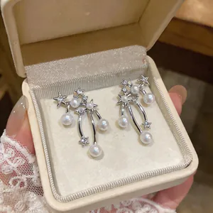 Detailed view of silver star and pearl drop earrings displayed in a luxury jewelry box.