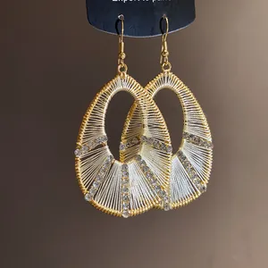 Close-up of elegant teardrop earrings with white thread wrap and crystal accents