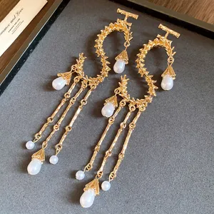 Primo piano di orecchini a frange in metallo dorato con eleganti perle a goccia d'acqua.