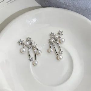 Elegant star pearl dangle earrings with sparkling zircon on a white ceramic plate