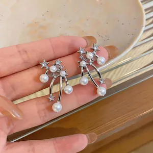 Close-up of star and pearl drop earrings with sparkling zircon detail
