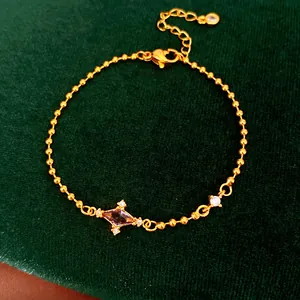 Detailed view of elegant gold ball chain bracelet featuring a purple rhombic zircon stone