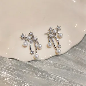 Detailed view of silver star and pearl drop earrings on a ceramic display plate.