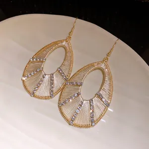 Detail of hollow teardrop earrings with sparkling rhinestones in gold-tone finish