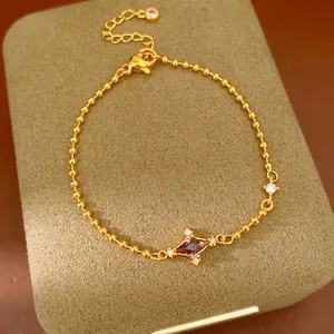Detailed macro view of a gold ball chain bracelet with a purple rhombus zircon pendant