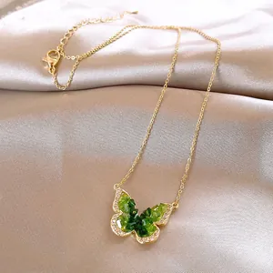 Detailed view of the gold necklace featuring a vibrant green gradient butterfly pendant.