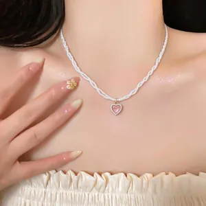 Close-up of a French style twisted pearl necklace featuring a pink heart pendant
