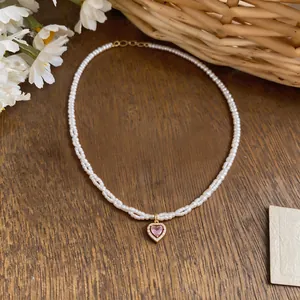 Detail of elegant pearl necklace with pink zircon heart pendant on wooden background.