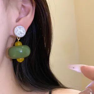Detailed view of stylish green resin dangle earrings with silver needles on a model