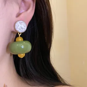 Detailed macro shot of vintage-inspired resin drop earrings with green and yellow beads