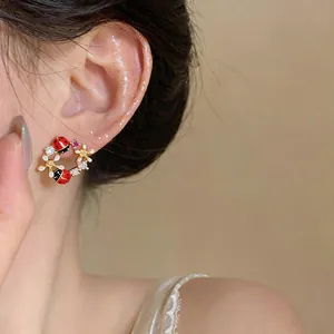 Primo piano di orecchini a lobo placcati in oro 18k con fiori, coccinelle e zirconi scintillanti
