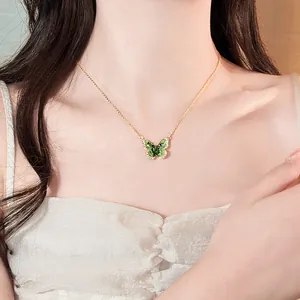 Close-up of an elegant green gradient butterfly pendant necklace worn by a model