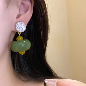 Detailed close-up of minimalist green resin pendant earrings worn on model's ear