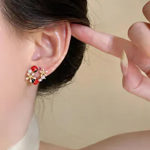 Primo piano di una modella che indossa dolci orecchini a lobo con coccinelle, fiori e zirconi.