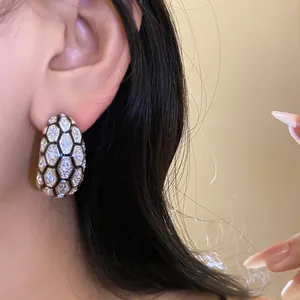 Close-up detail of 18k gold plated earrings featuring sparkling hexagonal zircon plaid.