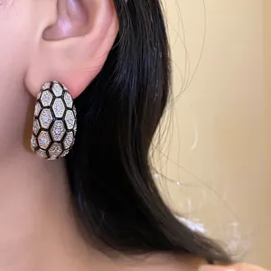 Close-up of vintage 18k gold plated hexagonal earrings with zircons and black enamel scales.
