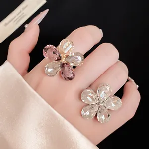 Close-up of sparkling rhinestone flower open rings on a model's hand