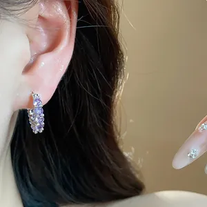 Detailed macro view of elegant silver hoop earrings with sparkling purple zircon stones