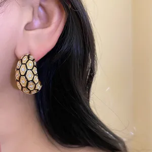 Detailed close-up of 18k gold-plated checkered earrings with sparkling zircons