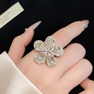 Detailed view of a sparkling five-petal crystal flower ring on a manicured hand