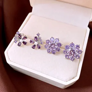 Exquisite purple zircon flower ear cuffs and earrings displayed in a cream jewelry box.