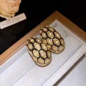 Close-up of 18k gold-plated checkered earrings with zircon details in jewelry box