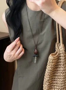 Vintage wood resin beaded pendant necklace worn with a straw bag