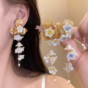 Detail view of elegant white pearl flower tassel earrings with golden leaf accents.