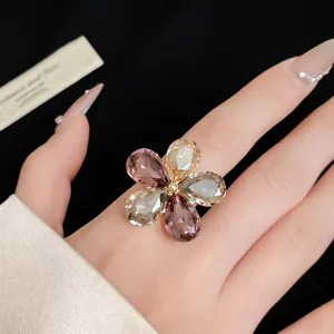 Close-up view of a luxury flower ring with multi-colored teardrop crystals worn on a finger