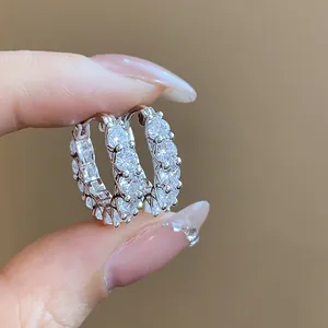 Macro view of detailed sparkling cubic zirconia stones set in silver hoop earrings.