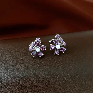 Elegant purple zircon flower ear cuffs with central pearl detail on dark leather