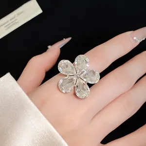 Close-up of a sparkling crystal flower open ring worn on a hand with elegant manicure.