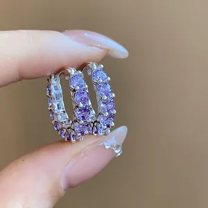 Close-up of elegant silver hoop earrings with sparkly purple zircon stones.