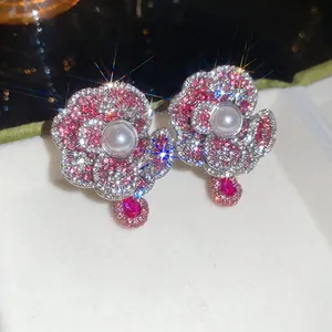 Detailed close-up of floral crystal earrings with central pearl and pink accents