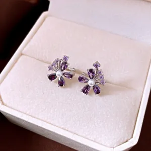Detailed macro view of elegant purple flower zircon ear bone clips with pearl accents
