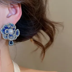 Close-up detail of vintage style floral earring with blue stones and a center pearl