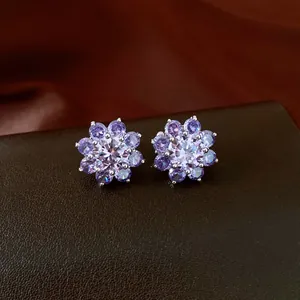 Detailed view of elegant purple zircon flower-shaped ear bone clips on leather texture.