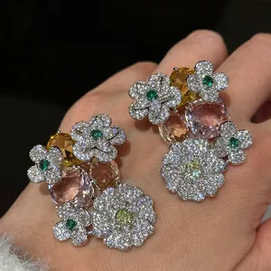 Close-up of sparkling floral stud earrings with large oval pink and yellow stones